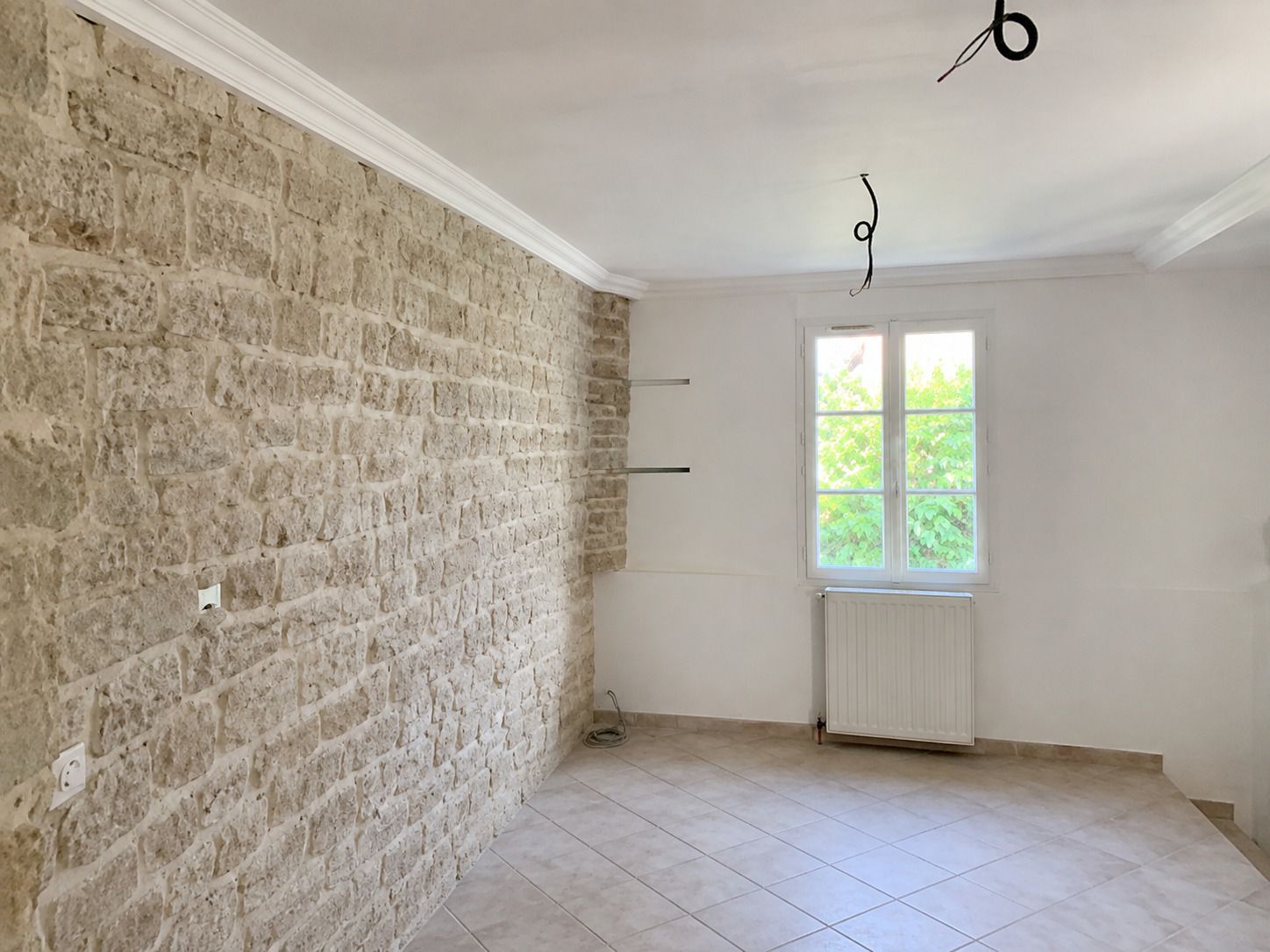 Piece renovee avec mur en pierre apparente conserve et lumiere naturelle.