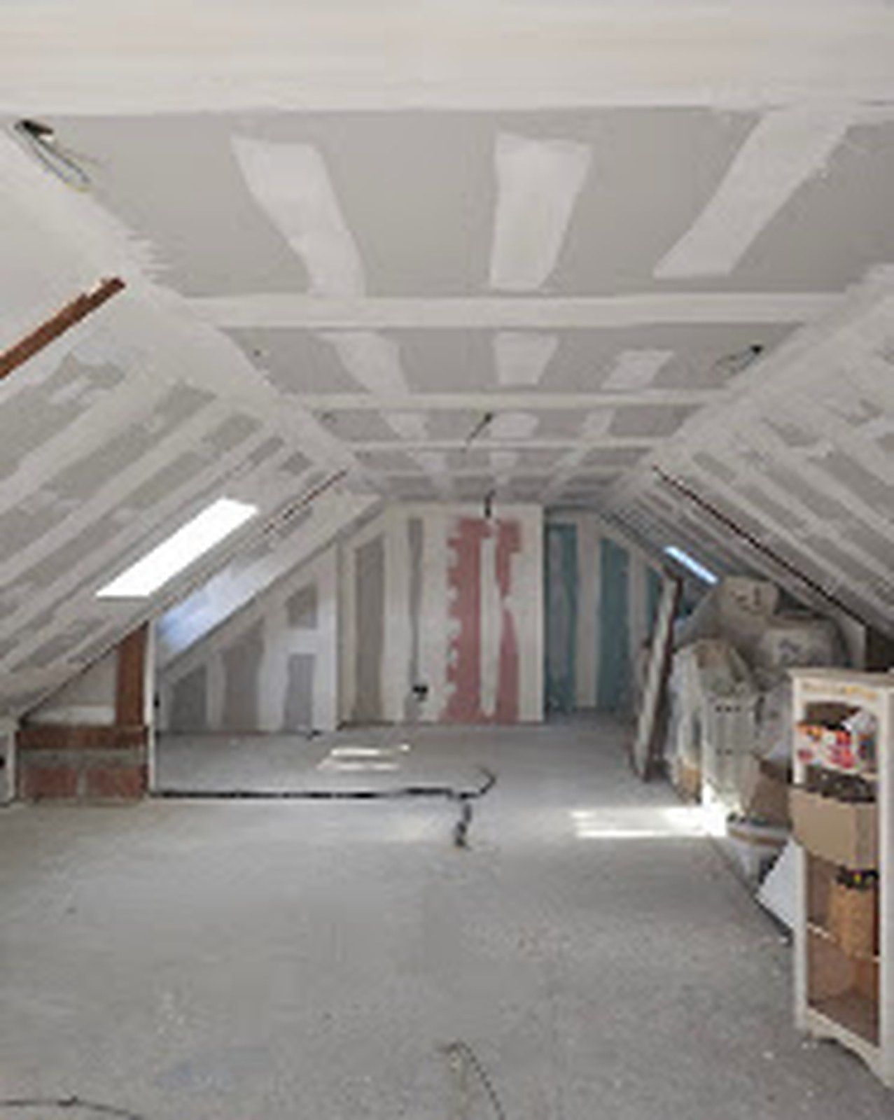 Combles aménagés avec isolation posée entre chevrons et fenêtre de toit.