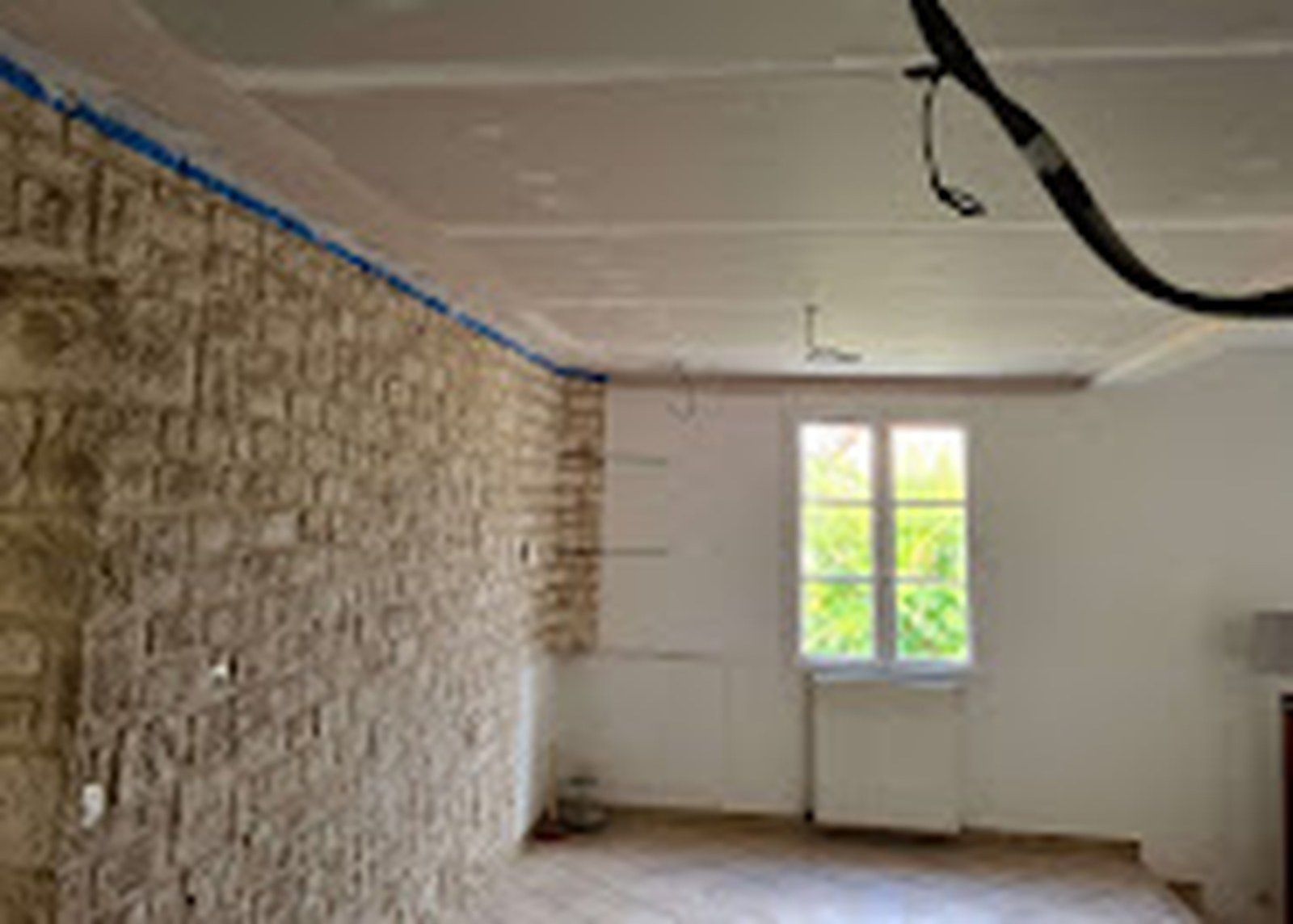 Mur en pierre apparente conservé dans une pièce rénovée.